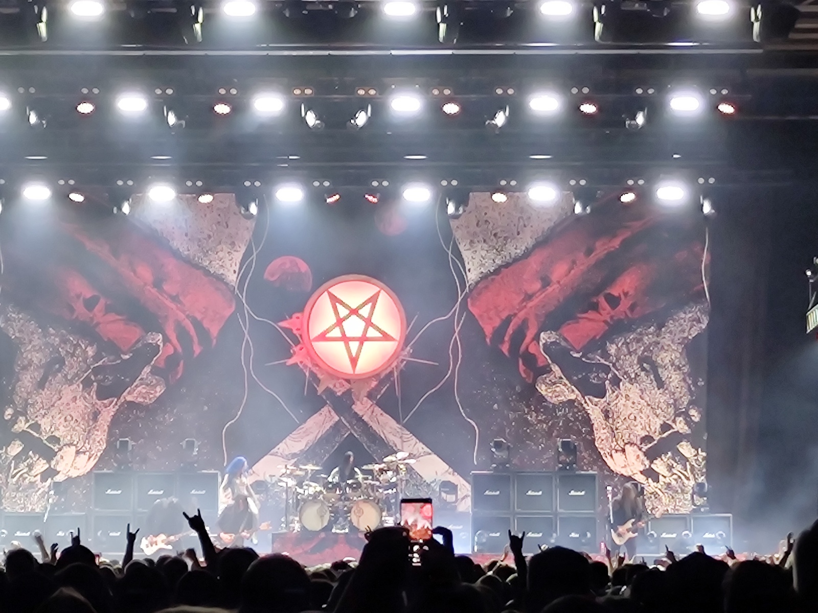 The stage backdrop for Arch Enemy, showing a pentagram and a skull left and right of it, photographed from afar